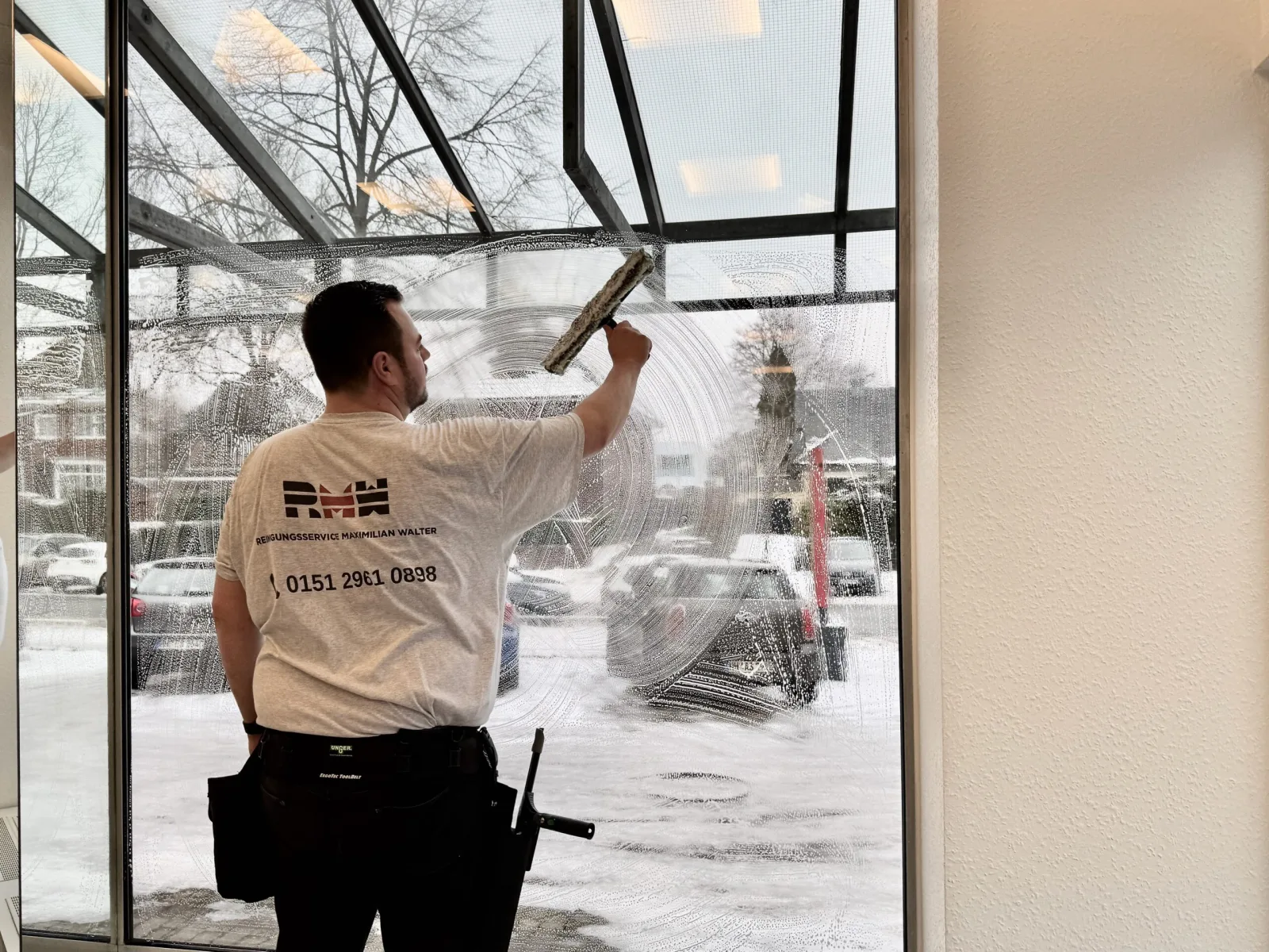 Maximilian Walter reinigt eine große Fensterfront in Volksdorf
